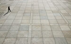 A man walking along a stone tile walkway.